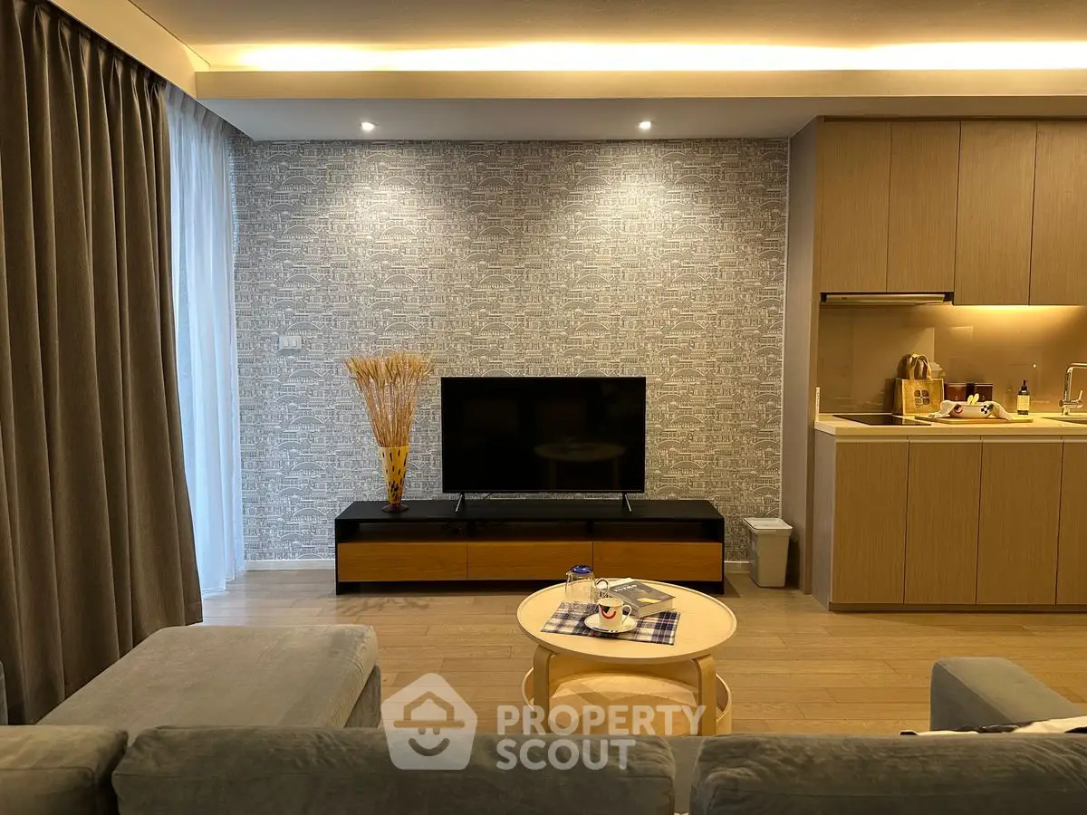 Modern living room with open kitchen, featuring sleek furniture and stylish decor.