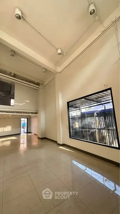 Spacious industrial-style room with high ceilings and large window