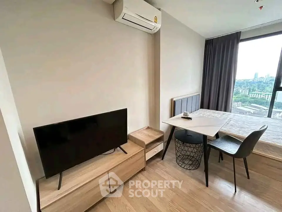 Modern studio apartment with sleek furniture and city view, featuring a TV and air conditioning.