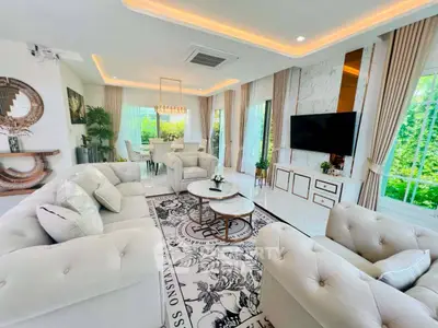 Luxurious living room with elegant decor, plush seating, and large windows offering lush garden views.