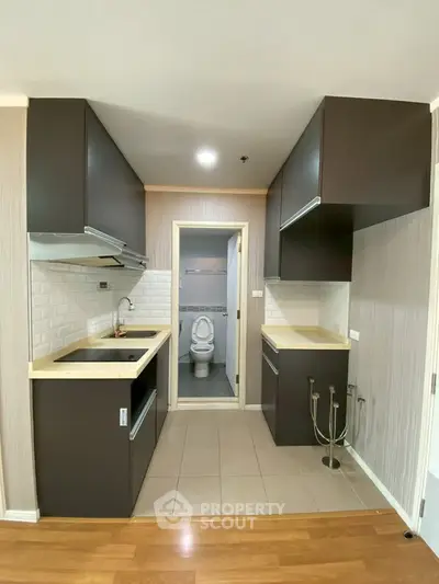 Modern kitchen with sleek cabinetry and open layout leading to a bathroom