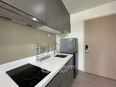 Modern compact kitchen with sleek cabinetry and stainless steel appliances in a contemporary apartment.