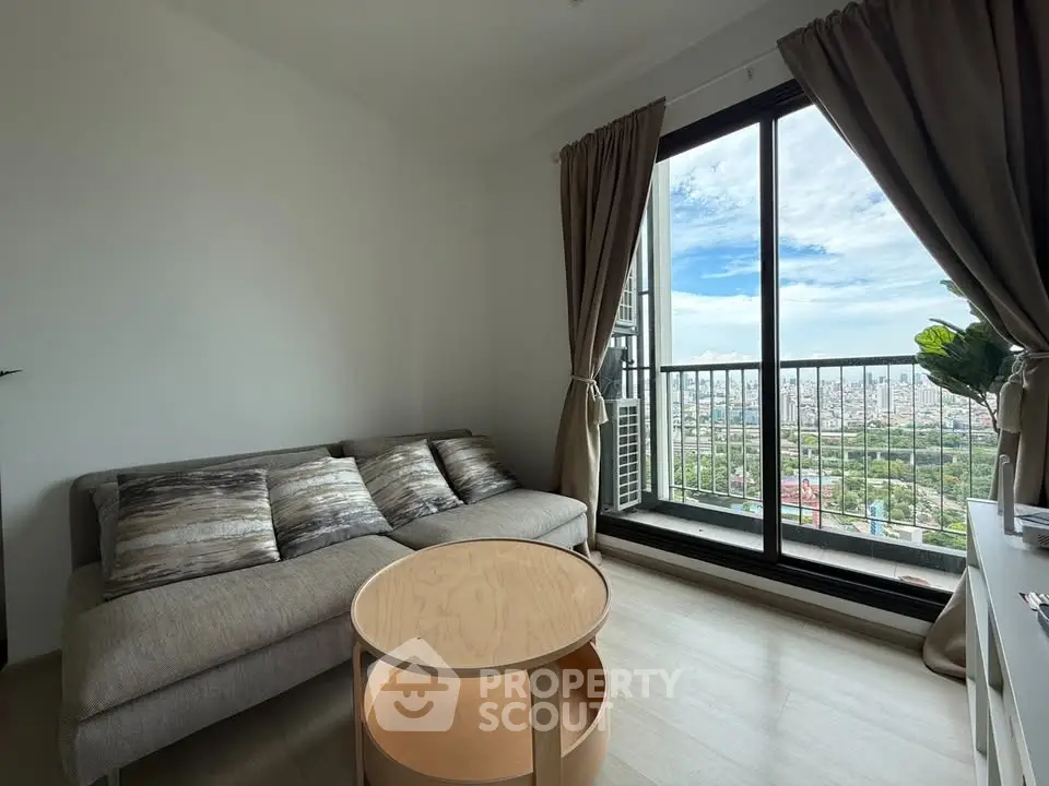 Modern living room with large window offering stunning city view and cozy sofa setup.