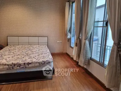 Spacious bedroom with elegant decor and large windows offering ample natural light.