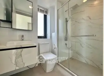 Modern bathroom with sleek design, featuring a glass shower and elegant marble finishes.