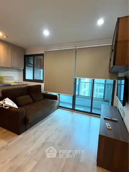 Modern living room with sleek furniture and large window overlooking cityscape.
