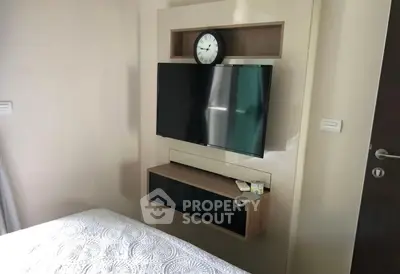 Modern bedroom with wall-mounted TV and stylish clock, perfect for cozy living.