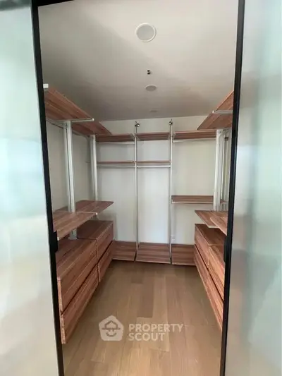 Spacious walk-in closet with wooden shelves and drawers, perfect for organized storage in a modern home.