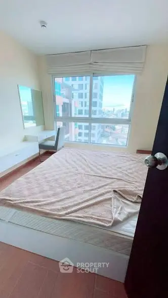 Bright bedroom with large window offering city view, modern furniture, and cozy ambiance.