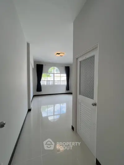 Spacious and bright room with large window and glossy tiled floor, perfect for customization.