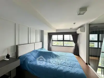 Spacious bedroom with large windows offering stunning city views and modern decor.