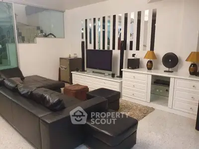 Stylish modern living room with black leather sofa and sleek entertainment center.