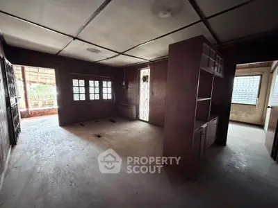 Spacious interior with wooden paneling and large windows, ideal for renovation.