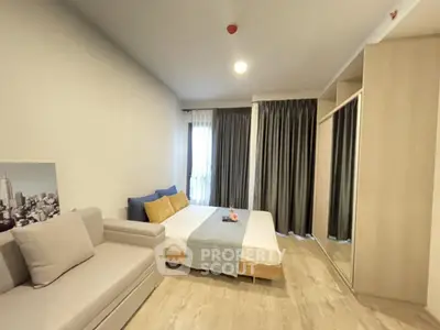 Modern bedroom with cozy bed, stylish sofa, and large mirrored wardrobe in bright apartment.