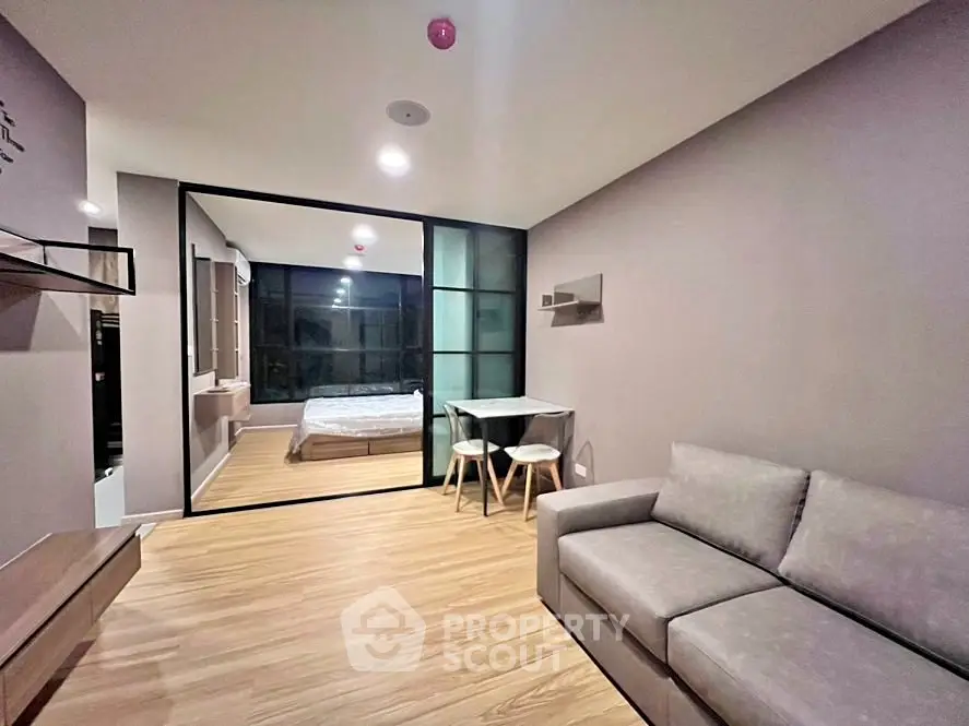 Modern living room with glass partition and cozy bedroom view