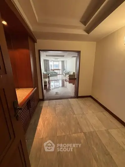 Spacious entryway leading to a bright living room with elegant furnishings and large windows.