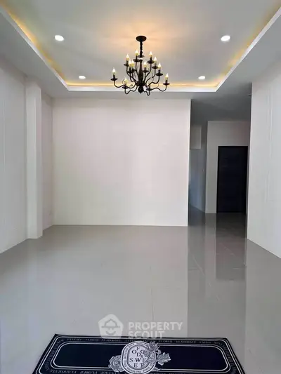 Spacious modern living room with elegant chandelier and glossy tile flooring.