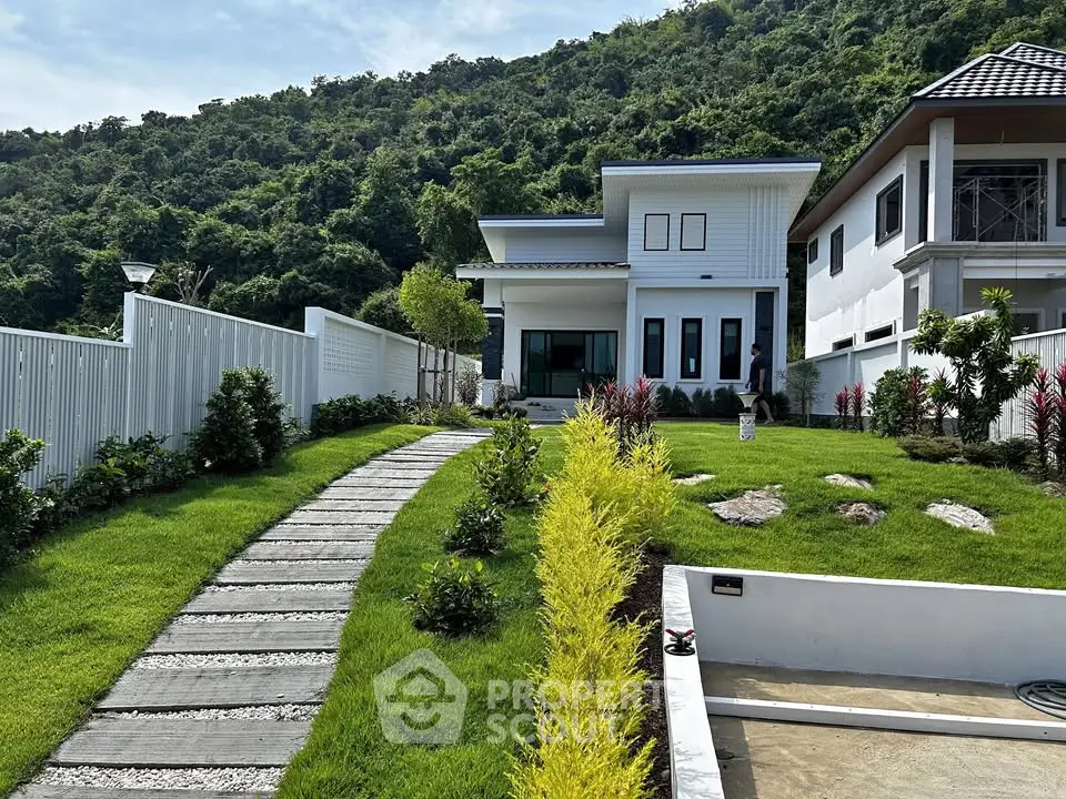 Modern hillside villa with lush garden and scenic mountain backdrop