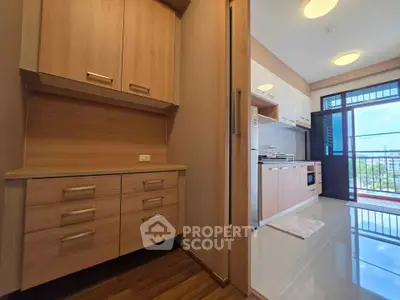 Modern kitchen with wooden cabinets and open layout leading to balcony with city view.