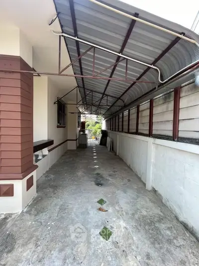 Covered outdoor walkway with metal roof and concrete floor in residential property