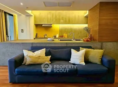Modern open-layout living room with stylish kitchen and cozy blue sofa.