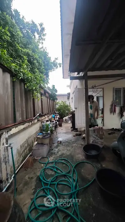 Charming outdoor space with potential for renovation, featuring a covered area and lush greenery.
