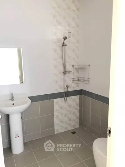 Modern bathroom with sleek shower and pedestal sink in neutral tones.