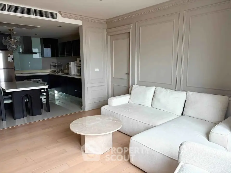 Elegant living room with open kitchen, featuring modern furniture and sleek design.