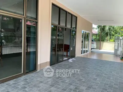 Spacious covered patio with large glass doors and tiled flooring, perfect for outdoor relaxation.