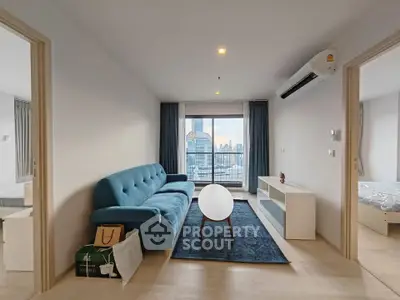 Modern living room with blue sofa and city view balcony in high-rise apartment.