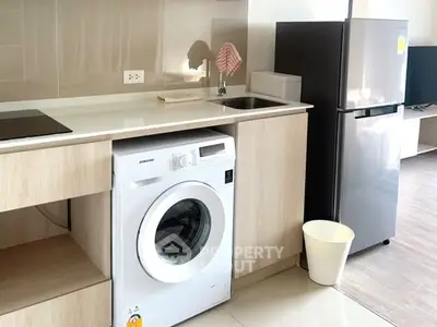 Modern kitchen with washing machine and fridge in sleek apartment.