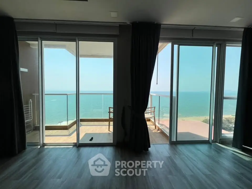 Stunning ocean view from modern apartment with spacious balcony and floor-to-ceiling windows.