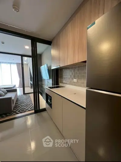 Modern kitchen with sleek cabinetry and open layout leading to stylish living room.
