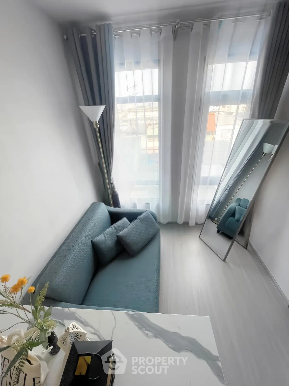 Modern living room with stylish blue sofa and floor-to-ceiling windows, featuring elegant decor and natural light.