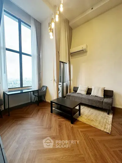 Spacious living room with high ceilings and large window offering city views.