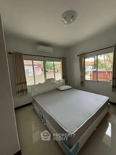Cozy bedroom with large windows and modern air conditioning unit, perfect for relaxation.