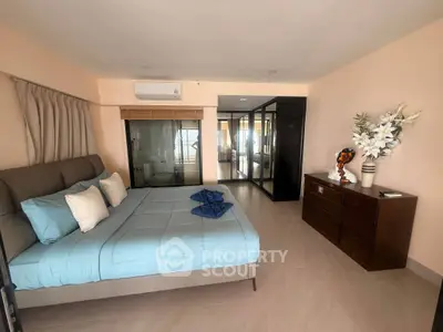 Spacious bedroom with modern decor and large windows offering natural light.