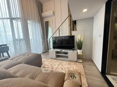 Modern living room with plush sofa, large TV, and floor-to-ceiling windows for natural light.