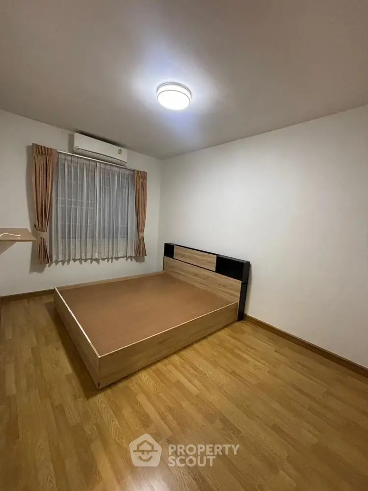 Spacious bedroom with wooden flooring and modern bed frame.