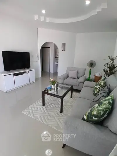 Spacious modern living room with sleek furniture and large TV, perfect for relaxation and entertainment.