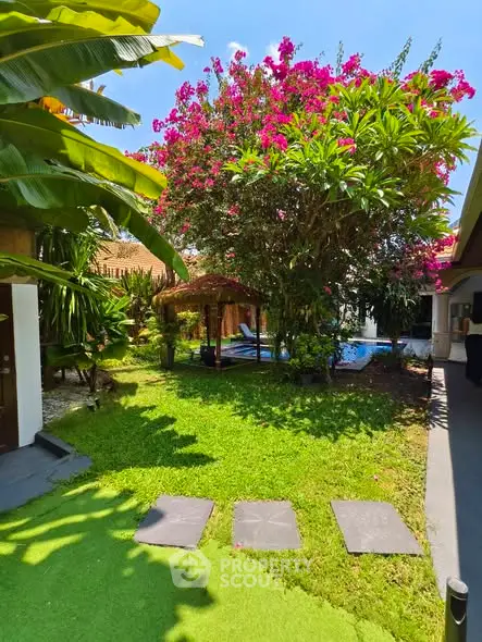 Lush tropical garden with vibrant flowers and cozy outdoor seating area, perfect for relaxation and leisure.