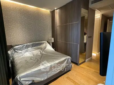 Modern bedroom with sleek design and wooden flooring, featuring a stylish bed and ambient lighting.