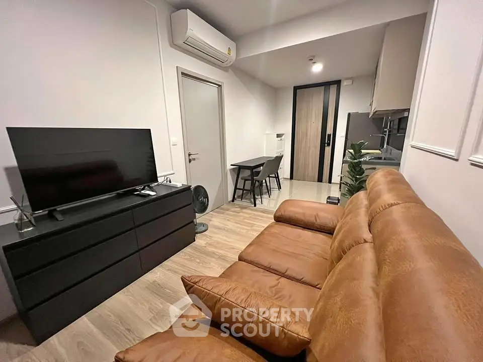 Modern living room with leather sofa and sleek TV setup in cozy apartment.