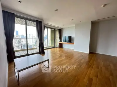 Spacious living room with wooden flooring and city view balcony in modern apartment.