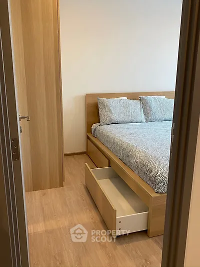Cozy bedroom with wooden flooring and modern bed frame featuring a convenient pull-out drawer.