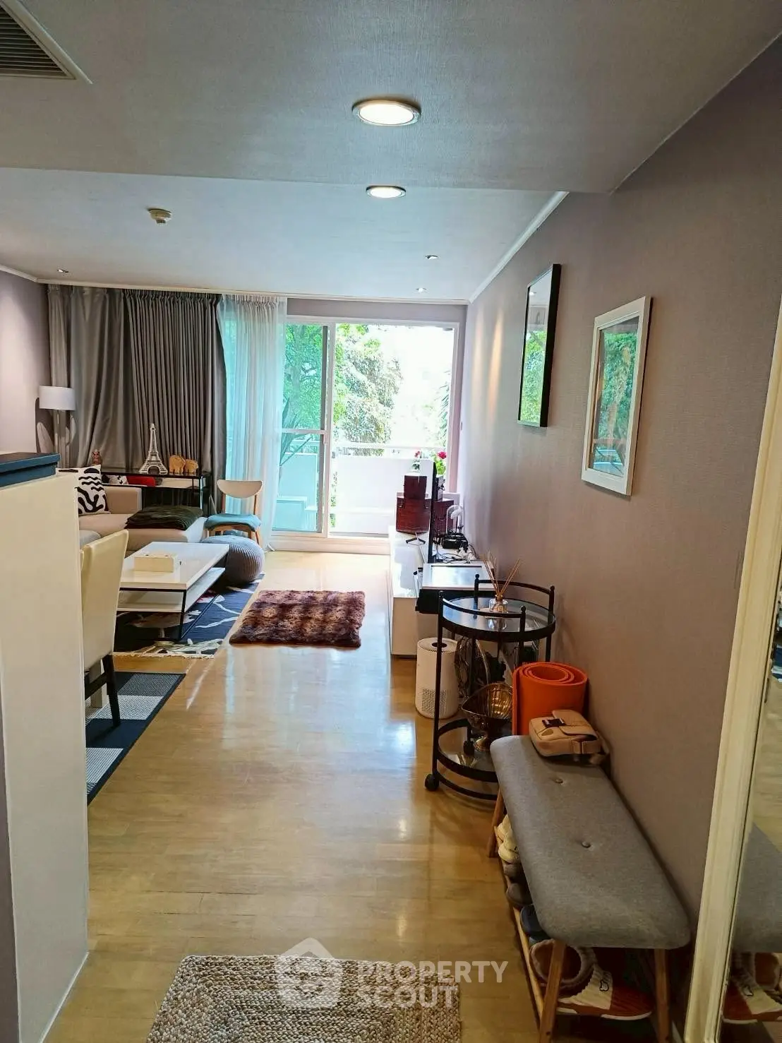 Spacious living room with modern decor and large windows opening to a balcony.