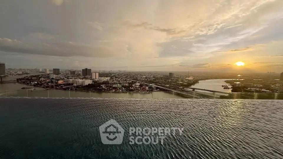 Stunning sunset view from infinity pool overlooking city skyline and river.