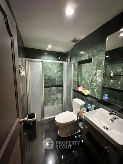 Luxurious bathroom with sleek black marble tiles and modern shower enclosure.