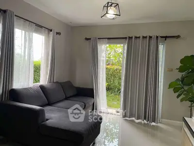 Cozy living room with modern gray sofa and large windows overlooking a lush garden.