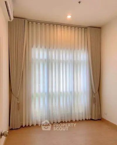 Spacious room with elegant floor-to-ceiling curtains and warm lighting, perfect for a cozy living space.